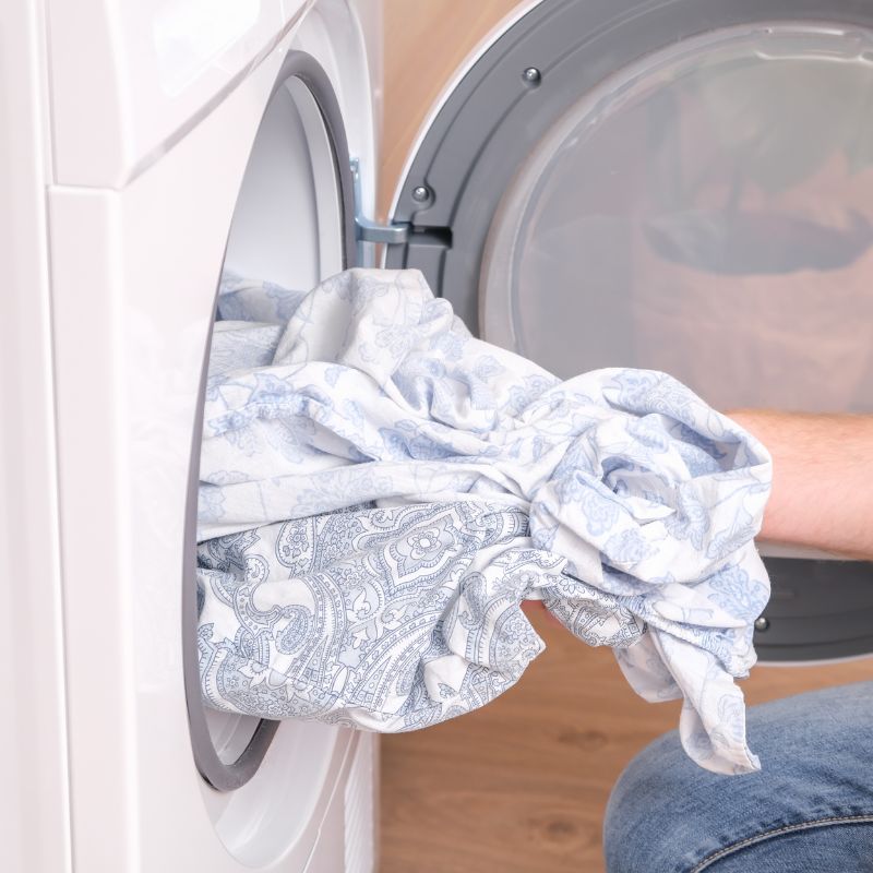 hand pulling sheets out of an open front-facing dryer