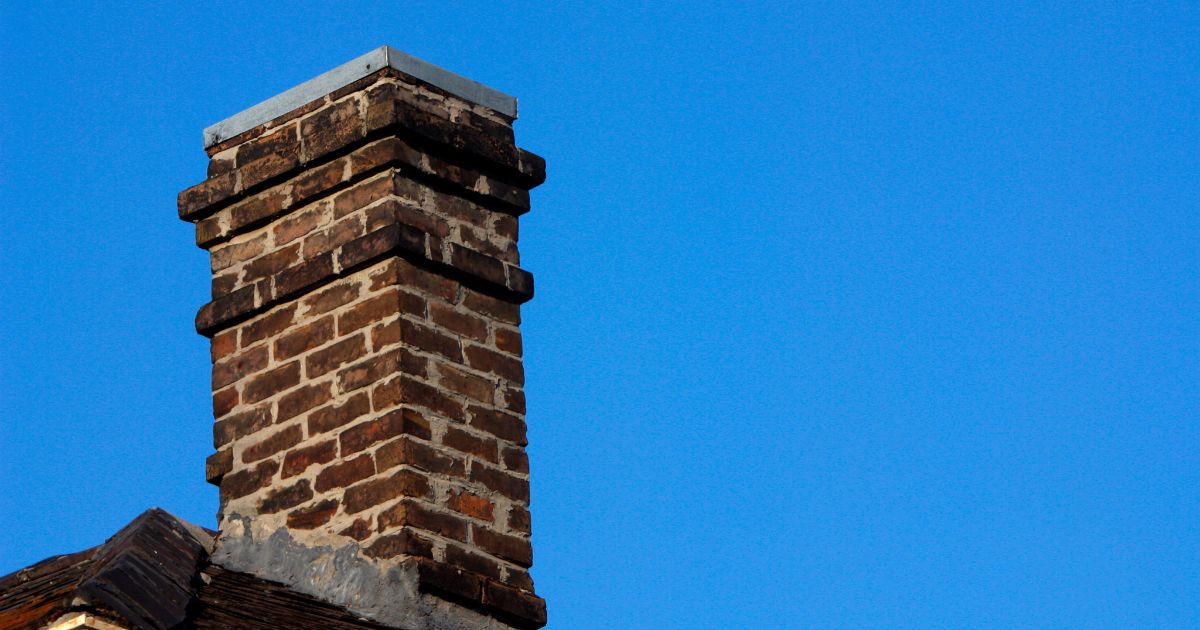 dark brick masonry chimney against a bright blue sky