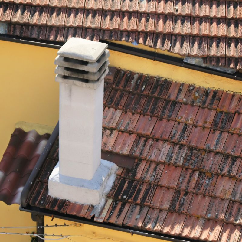 white stucco chimney on an old brown and red roof