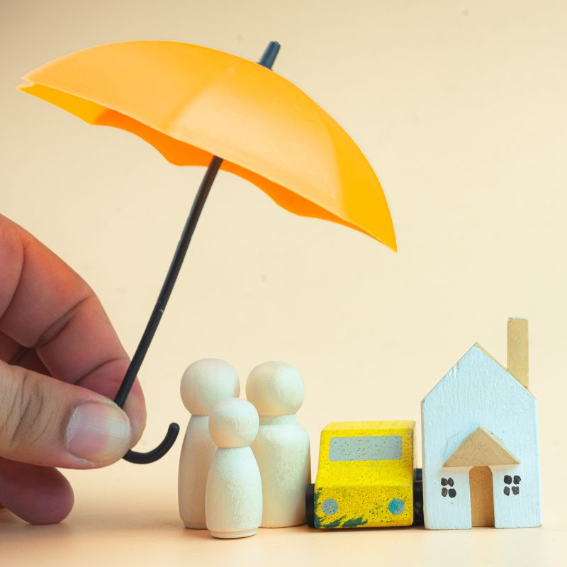 a hand hold a small umbrella over clay people, house, and car