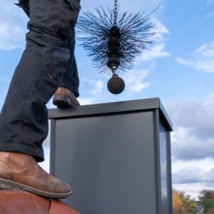 chimney tech putting a wire sweeping brush into the top of a chimney flue