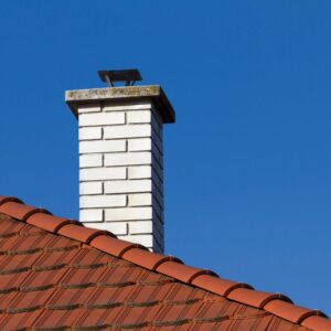 %Title% | Sureglow Stove &Amp; Chimney a white brick chimney coming off a red roof with a blue sky in the background