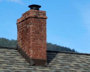%Title% | Sureglow Stove &Amp; Chimney A spalling chimney with a blue sky and the tops of trees in the background